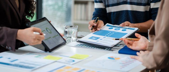 Business team using a calculator to calculate the numbers of statistic business profits growth rate on documents graph data, desk in the office.